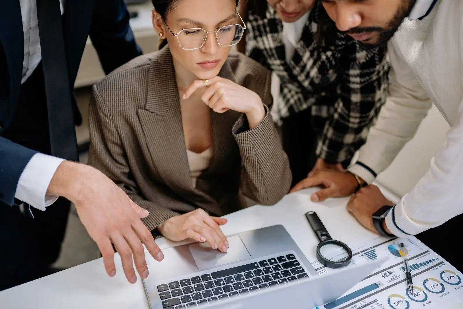 A team gathered around a laptop reviewing work together