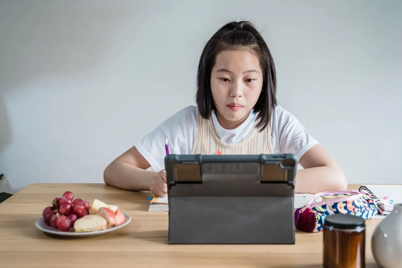 A school student studying at a table with a tablet