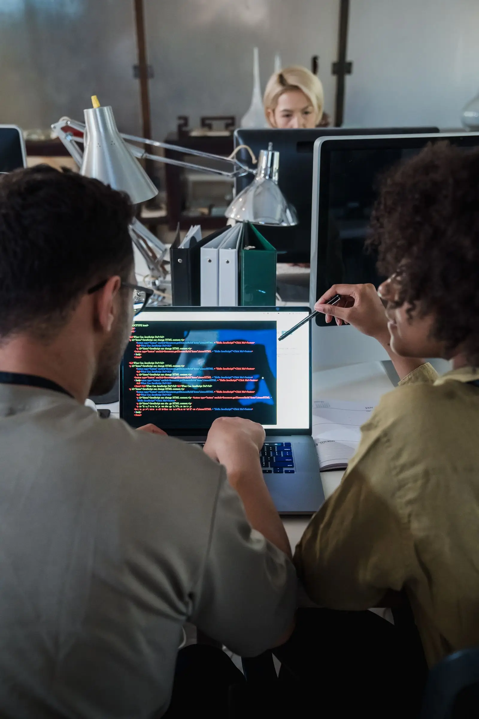 Two software developers reviewing code together on a laptop